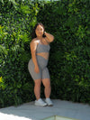Yena in the Cloud Light Grey Bike Shorts & Majestic Bra, modelling infront of a green wall.